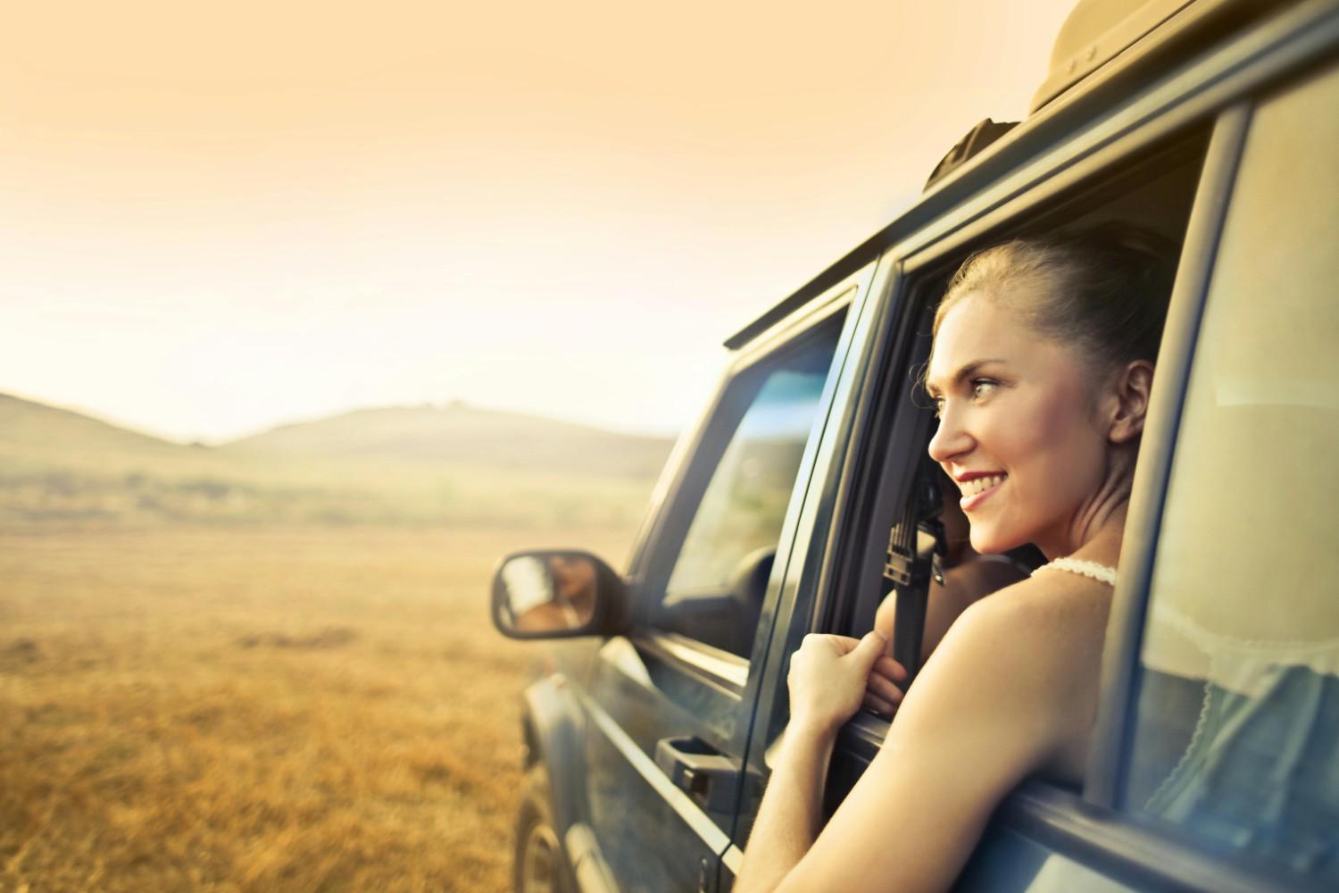 Happy driver smiling behind the wheel of a car after finding affordable auto insurance coverage
